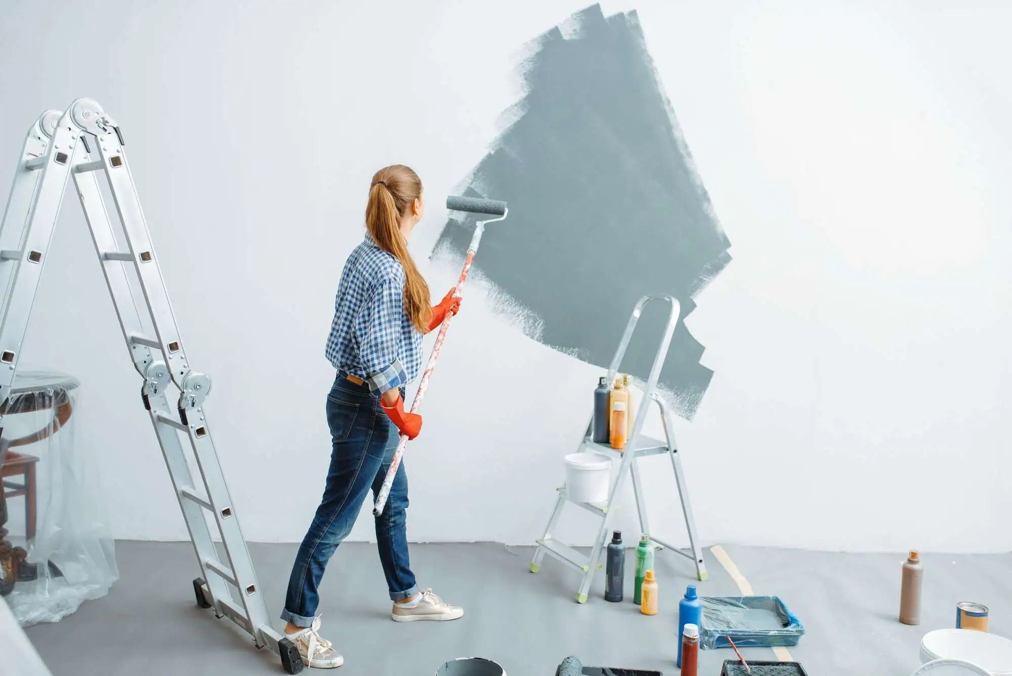 Woman painting wall with roller in a home renovation project.