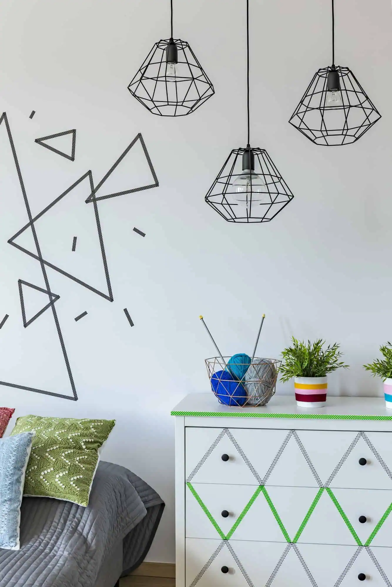 Pendant lights with black wireframe design hanging above a white dresser.